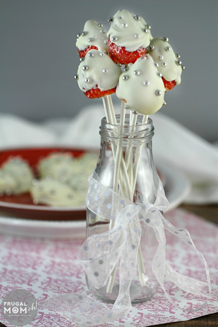 White Chocolate Covered Strawberry Pops dotted with silver nonpareils are perfect for a Valentine's Day or Date Night Dessert.  They also look great as part of a Valentines Day tablescape!