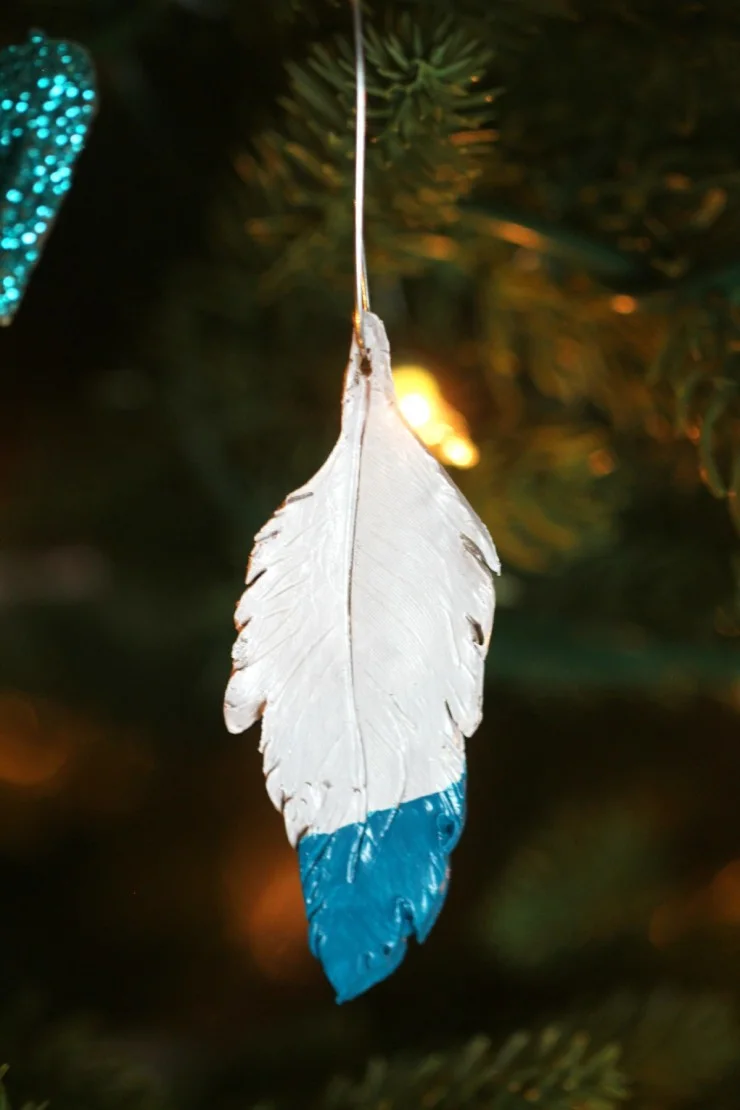 These Teal Dipped Feather Ornaments use oven-bake clay and paint to create realistic looking feathers to hang from your Christmas tree. These homemade ornaments are super easy to make!