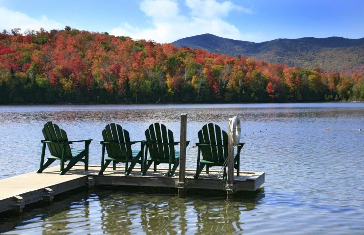 Adirondack chairs on a swim dock, on a peaceful lake in the Adirondack State Park in New York State.