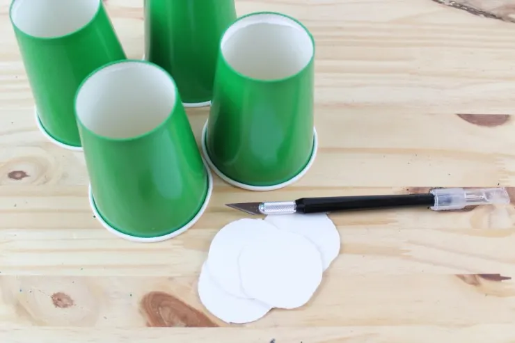 Using an exacto knife to cut the bottoms out of the cups.