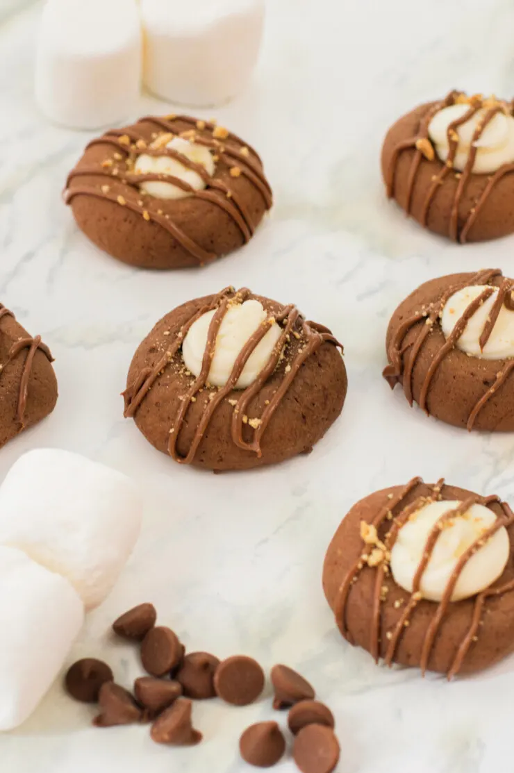 These easy to make S'mores Thumbprint Cookies features all the flavours of that favourite summertime camping treat.  A delectable chocolate cookie filled with marshmallow and topped with graham crackers and a chocolate drizzle.