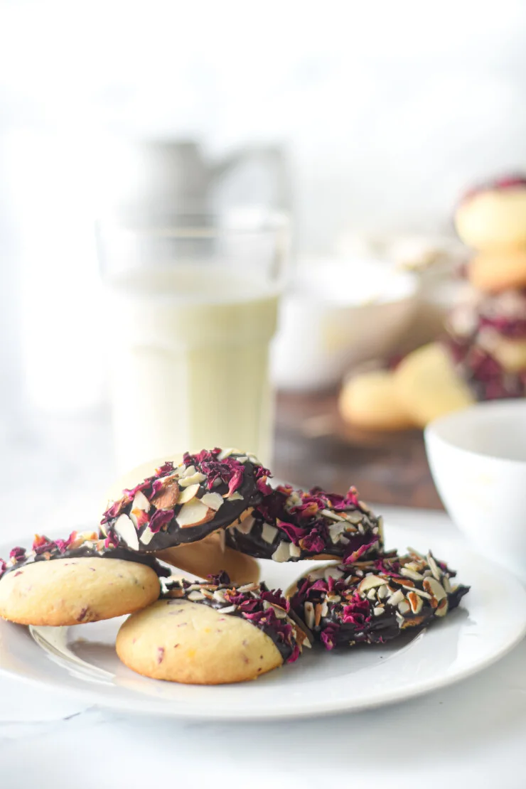 Fragrant Vanilla & Rose Shortbread Cookies are dipped in chocolate and sprinkled with rose petals and almonds in this tasty cookie recipe.