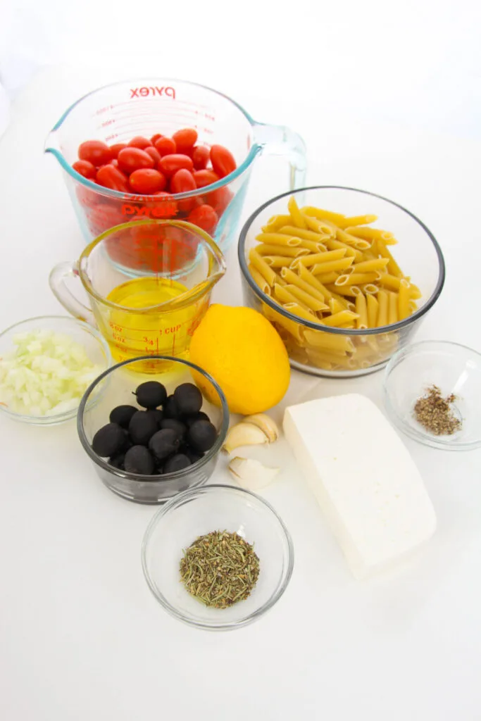 Ingredients for Baked Feta Pasta - Cherry Tomatoes, Pasta, Oil, Lemon, Olives, Herbs, Feta Cheese, Garlic, and onion.