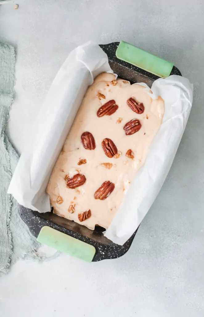 Fudge decorated with pecans inside a loaf pan.
