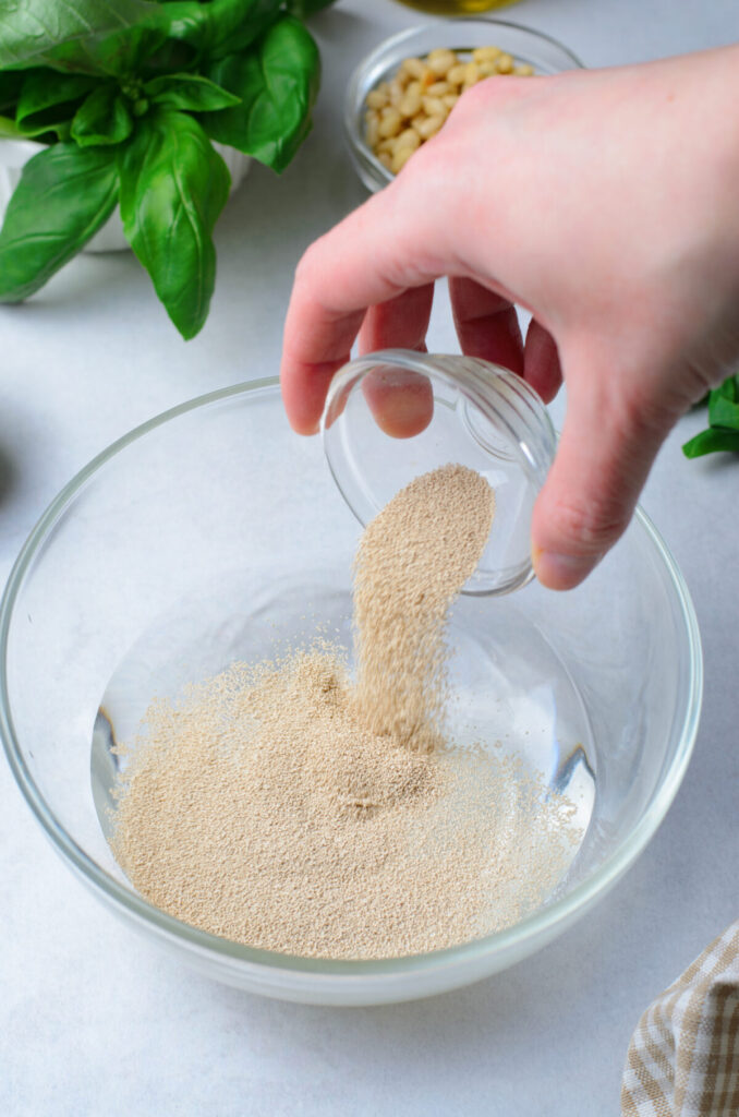 In a large bowl or a bowl of a stand mixer, combine the warm water, 1 tablespoon sugar, and yeast. 