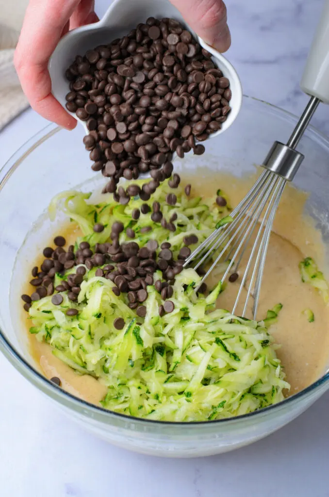 Batter in a bowl with chocolate chips and shredded zucchini.