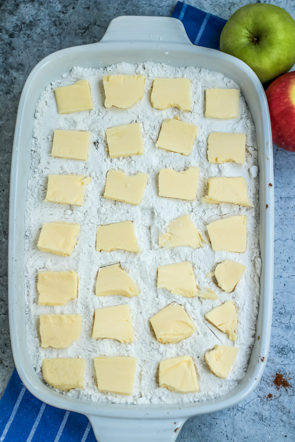 Squares of butter spread across the baking dish on top of the cake mix,.