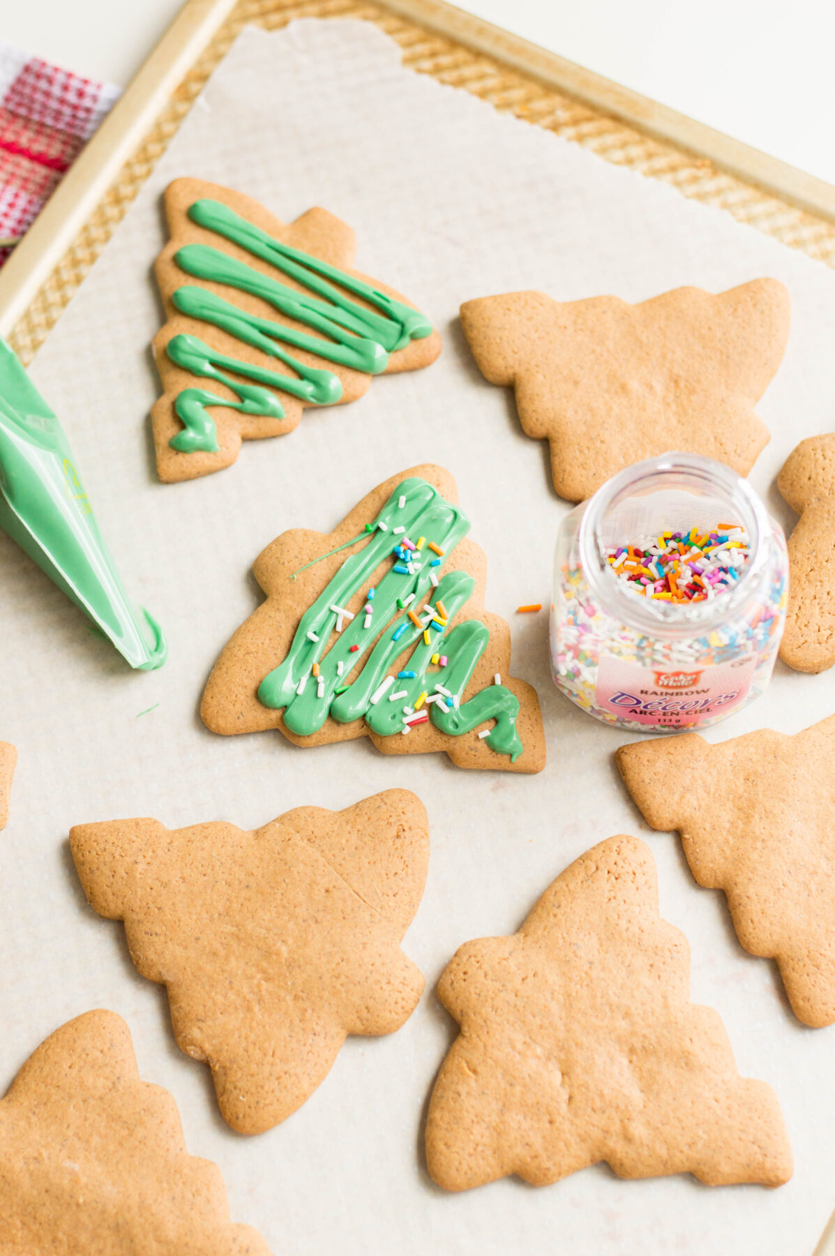 Decorating the gingerbread cookies with green candy melts and rainbow sprinkles.