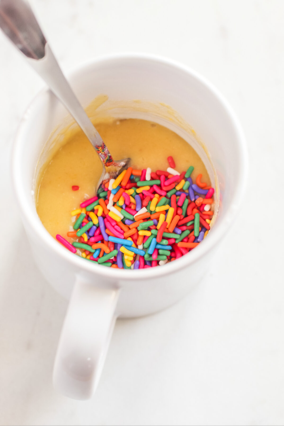 Sprinkles on top of the batter in the mug.