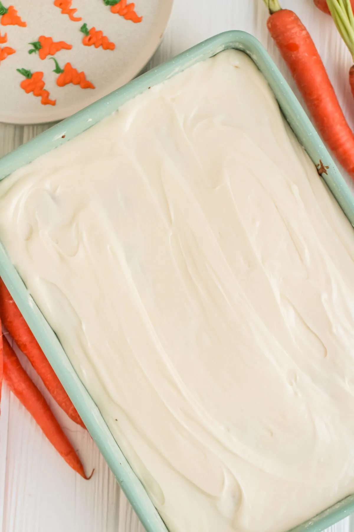 cream cheese frosting spread out over carrot cake.