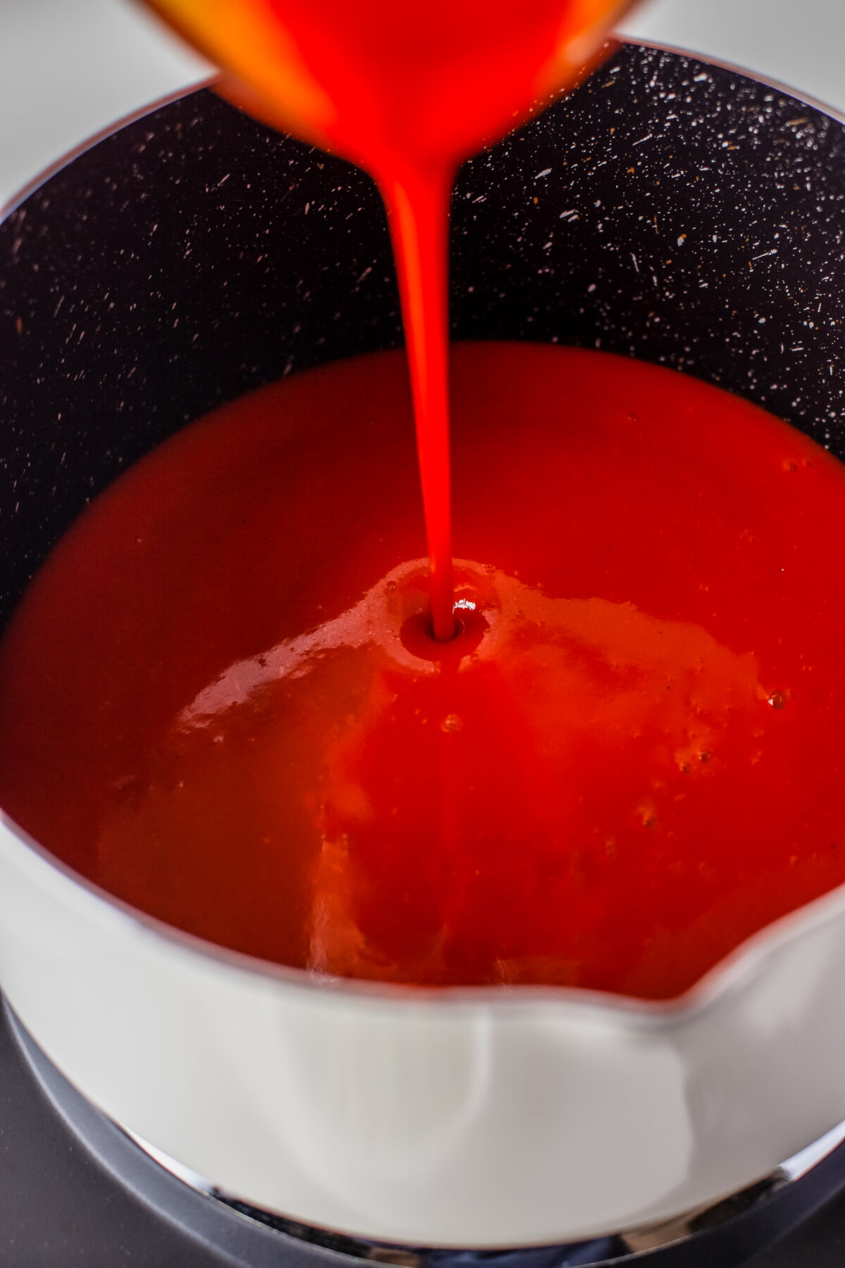 Hot sauce being poured into a saucepan;.
