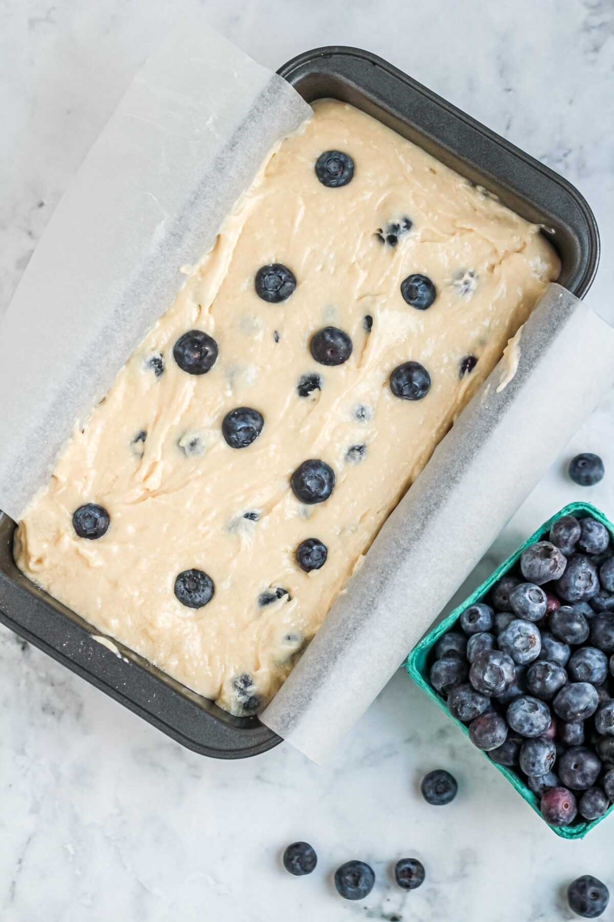 Loaf pan filled with blueberry batter,