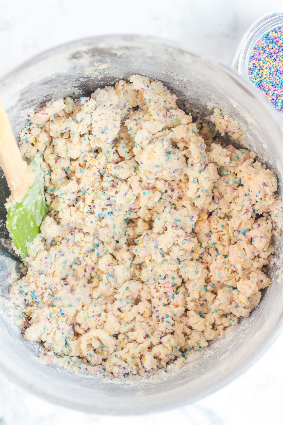 Dough with sprinkles in a mixing bowl.;