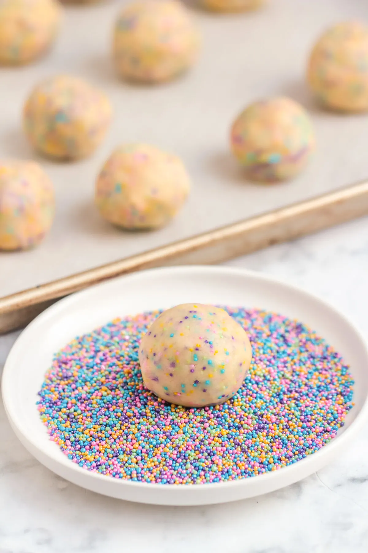 Rolling the dough balls in sprinkles.