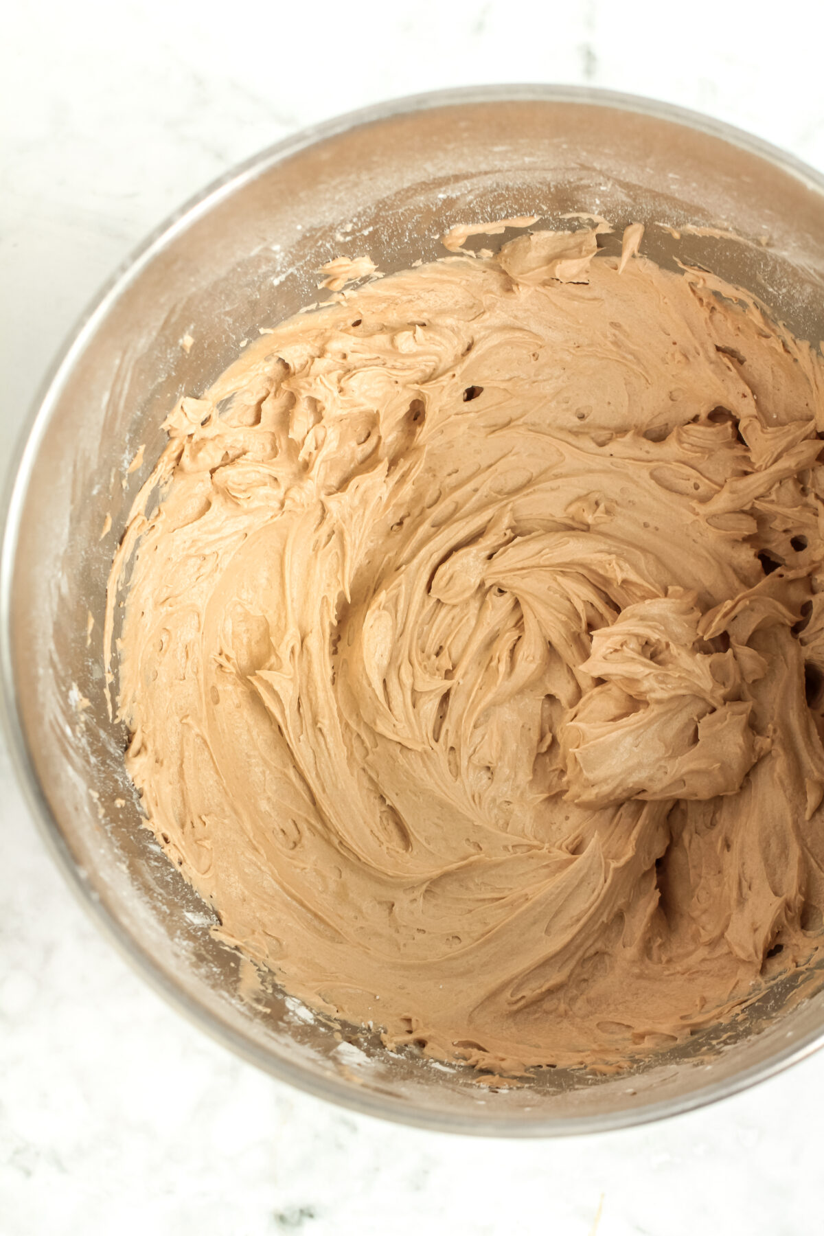 Mocha buttercream whipped together in a stand mixer bowl.