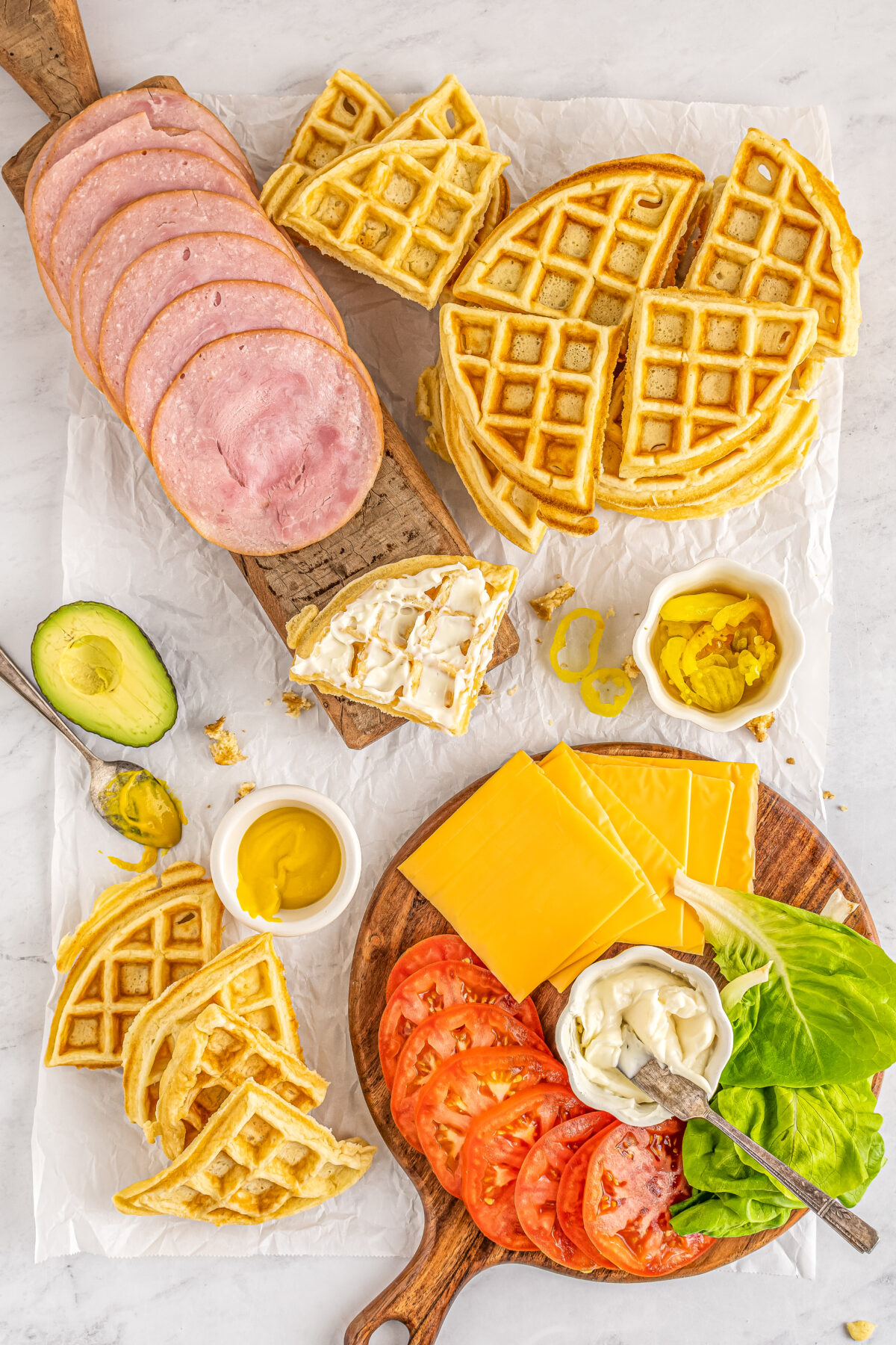 Mayo spread over a quarter of a waffle with other filling ingredients and waffle quarters laid out.