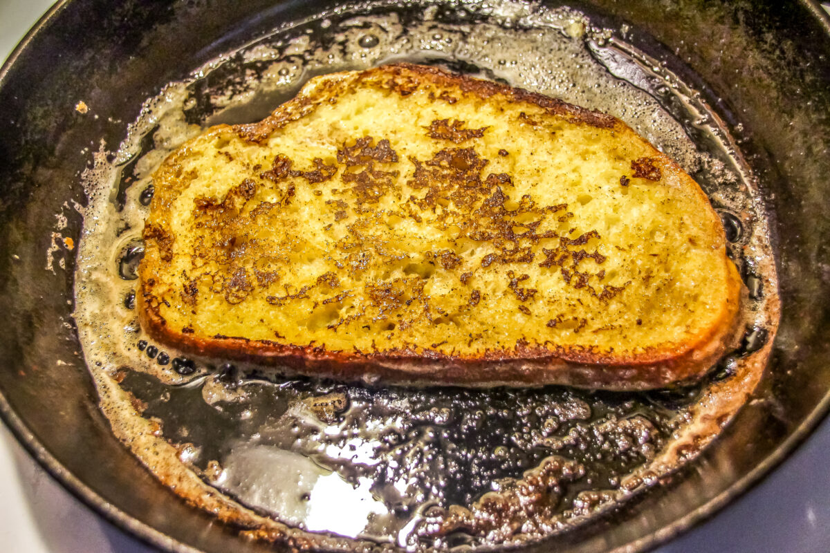 French toast frying in a cast iron skillet.