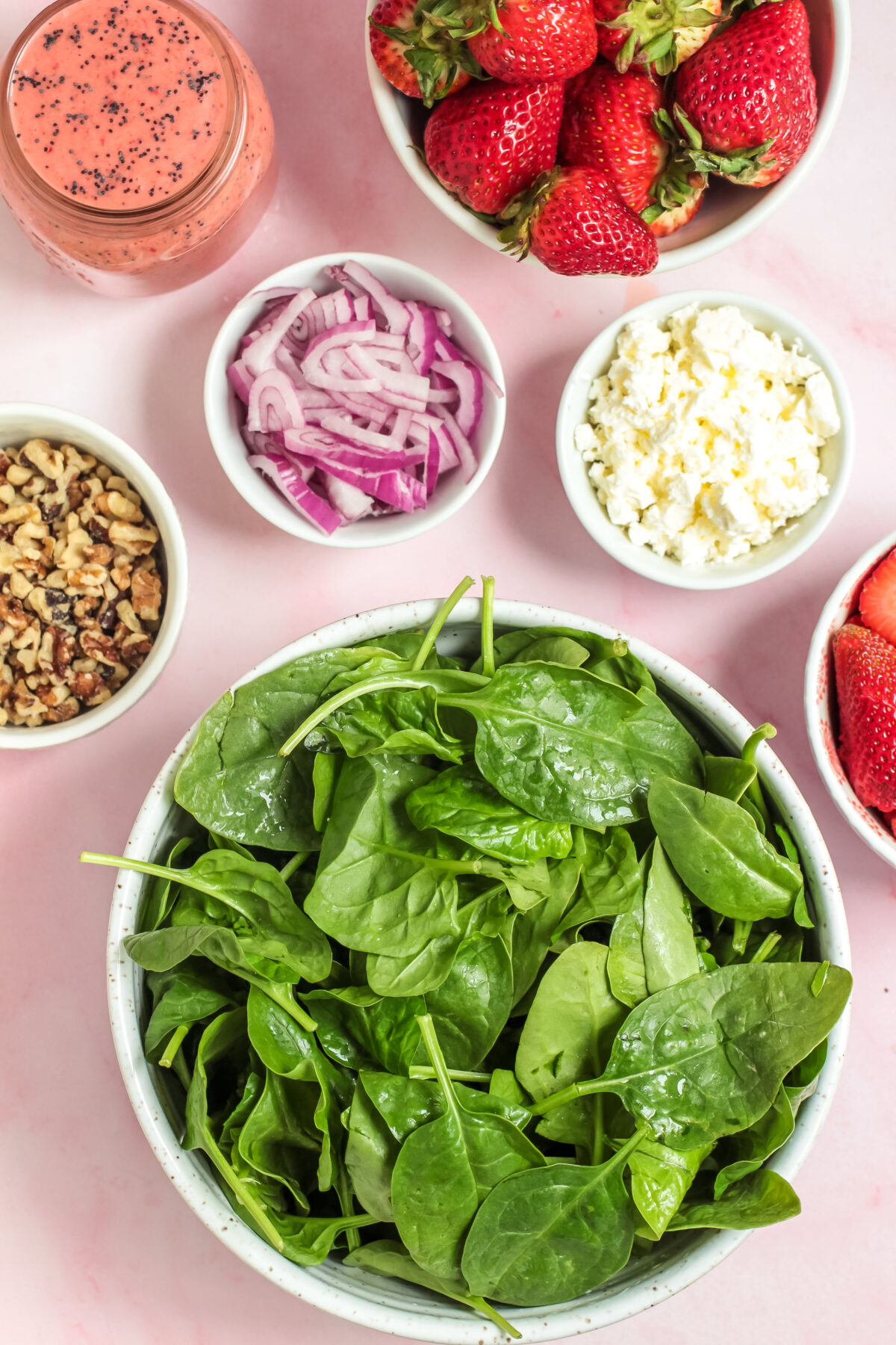 Ingredients for strawberry spinach salad in individual bowls.