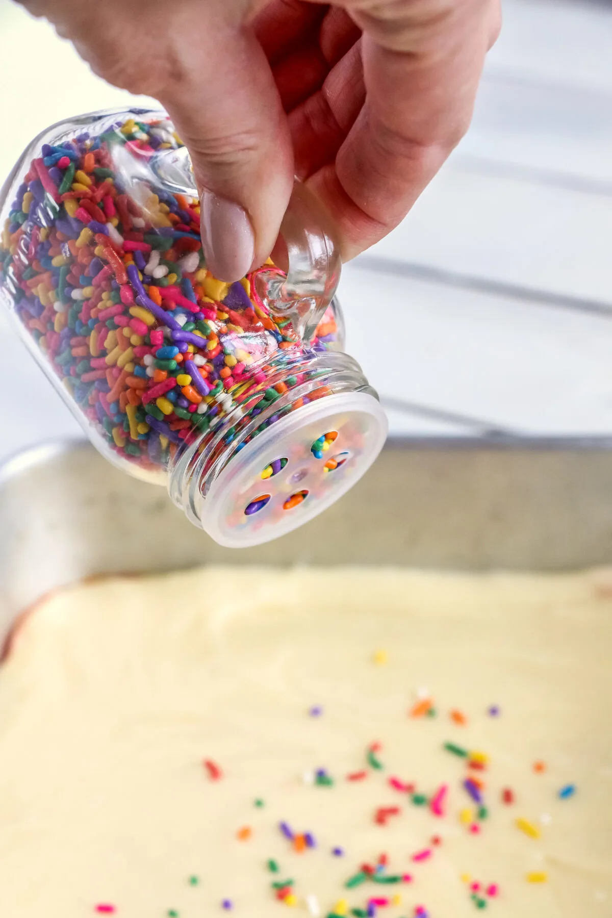 Funfetti sprinkles being poured over the unbaked bar