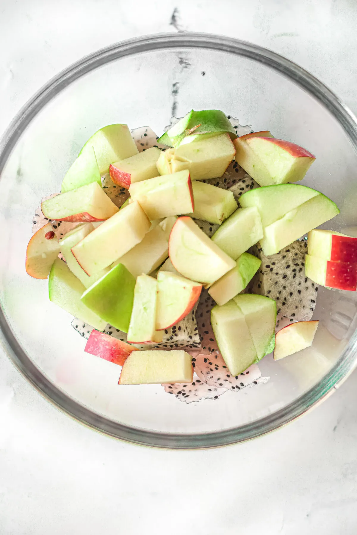 Place the cubed dragon fruit, red apple, and green apple into a large bowl.