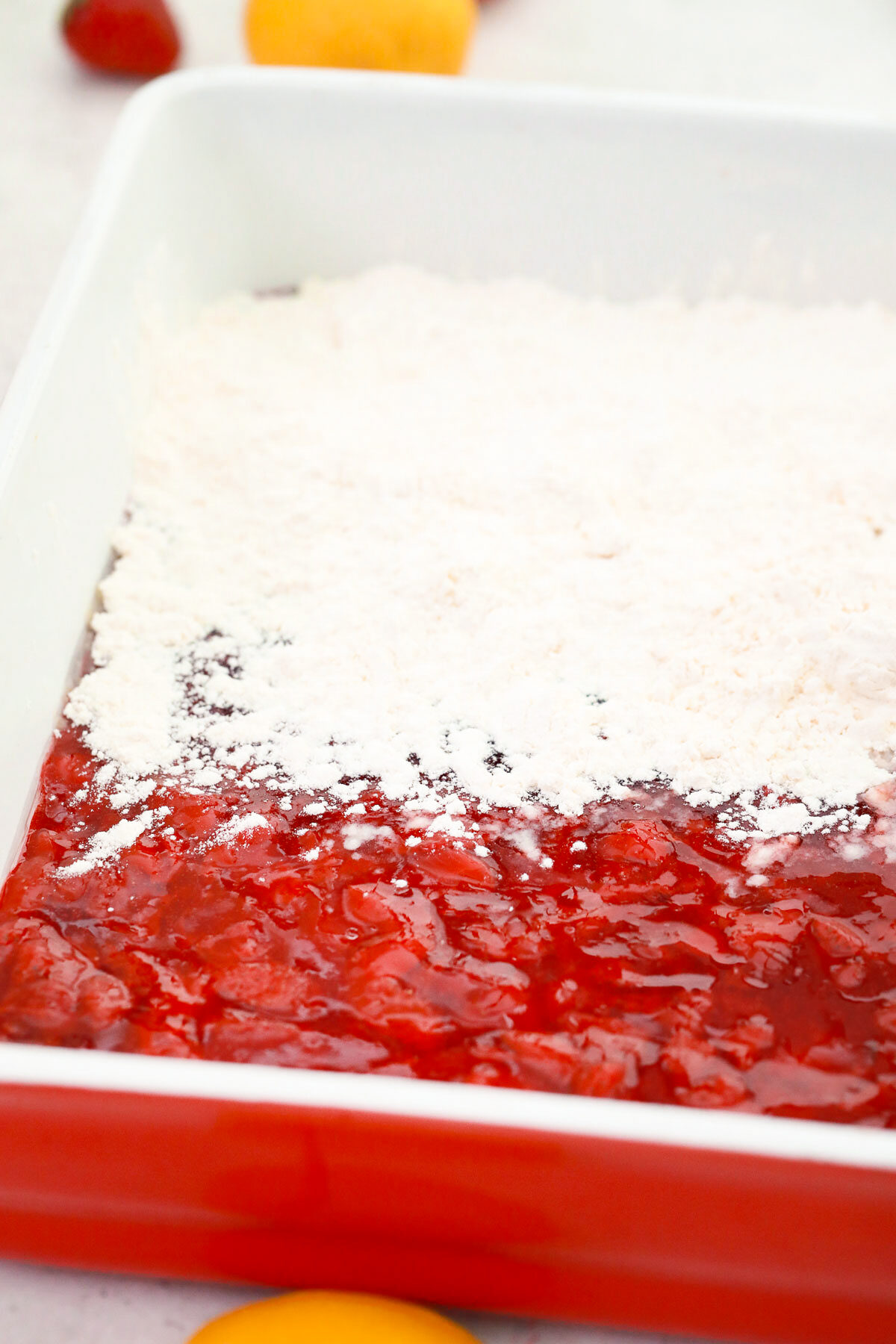 Sprinkling cake mix over the strawberry pie filling.