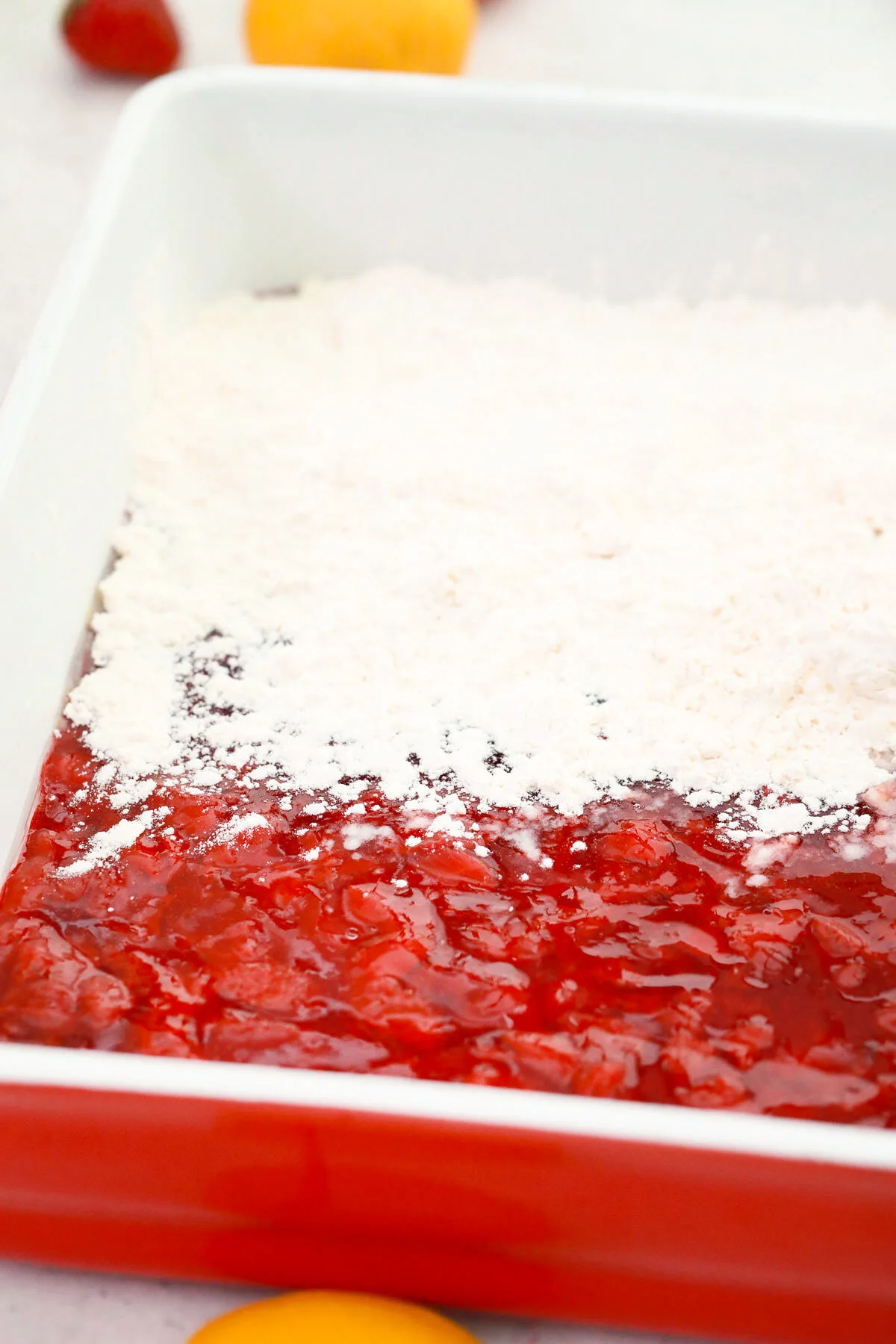 Sprinkling cake mix over the strawberry pie filling.