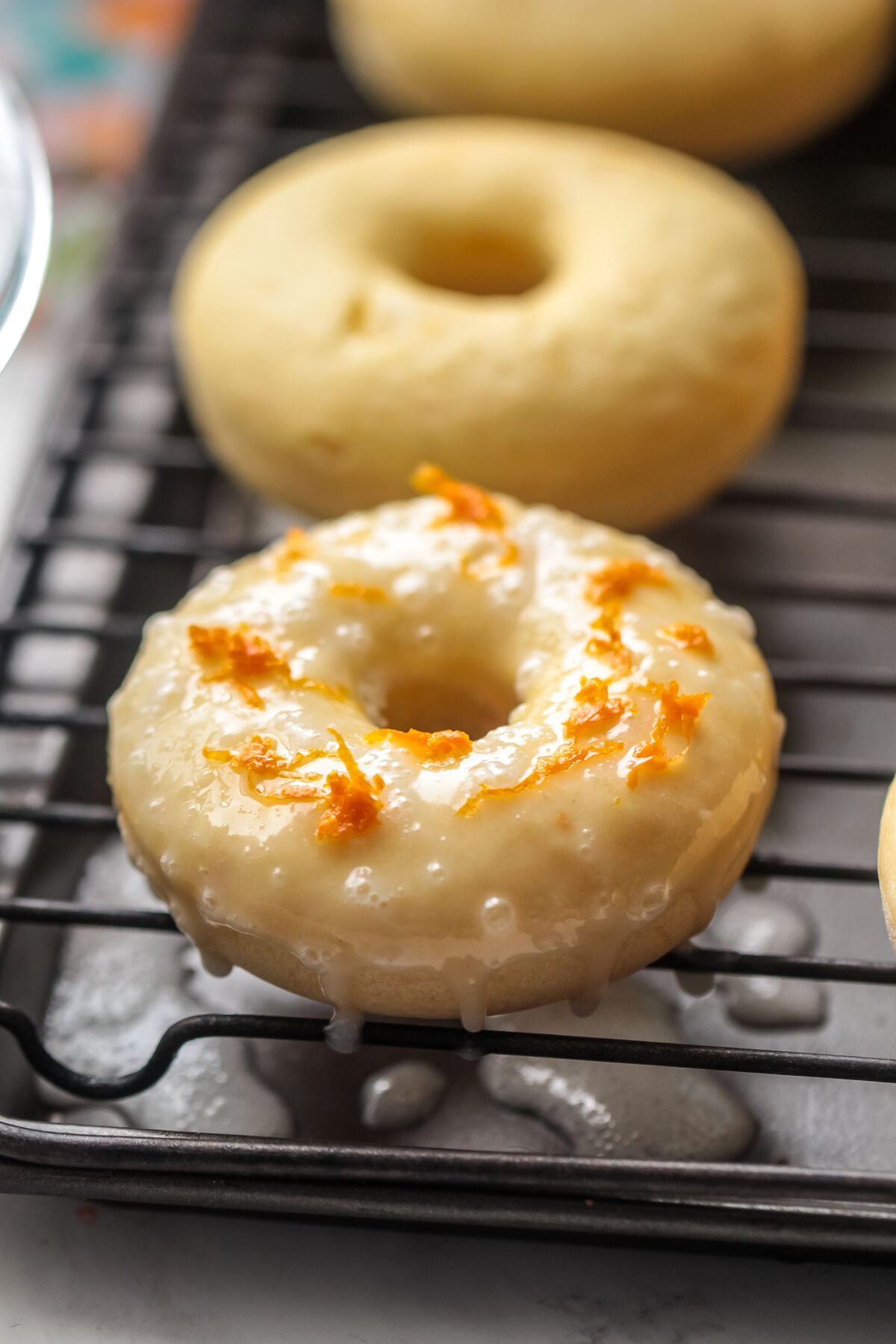Zest sprinkled over the glaze of an orange donut.