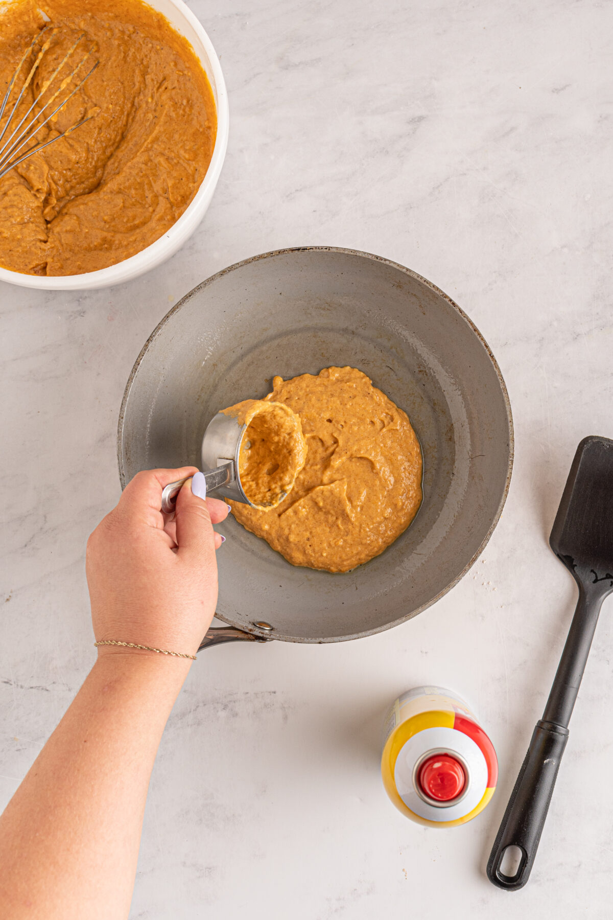Adding pumpkin batter to the heated skillet,