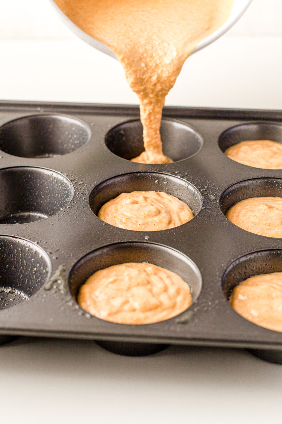 Filling the muffin tin with the batter.