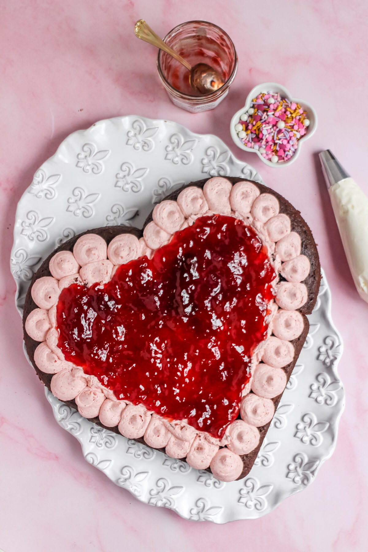 Strawberry jam in a layer over the frosting on the heart shaped cake.