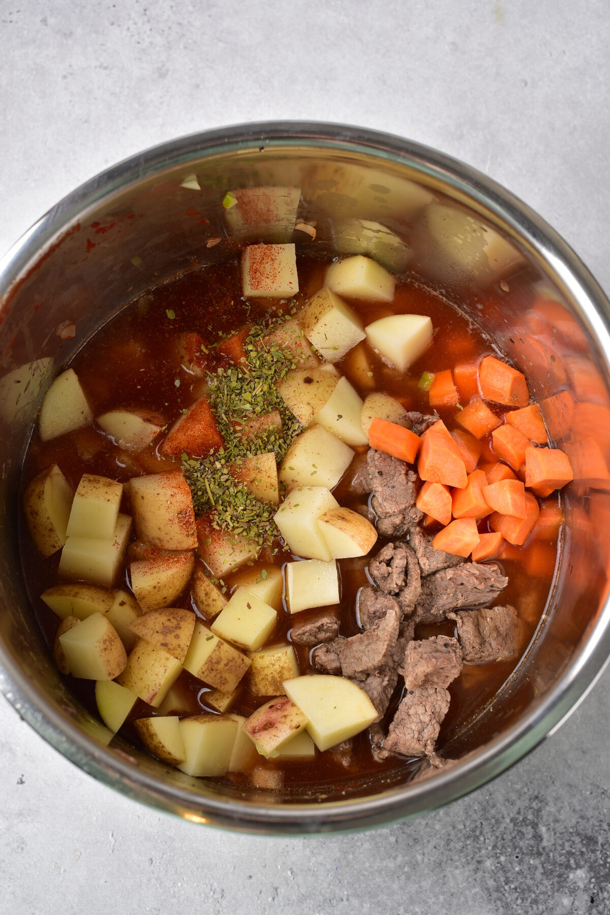 Potatoes, carrots, beef, and seasonings added to the instant pot.