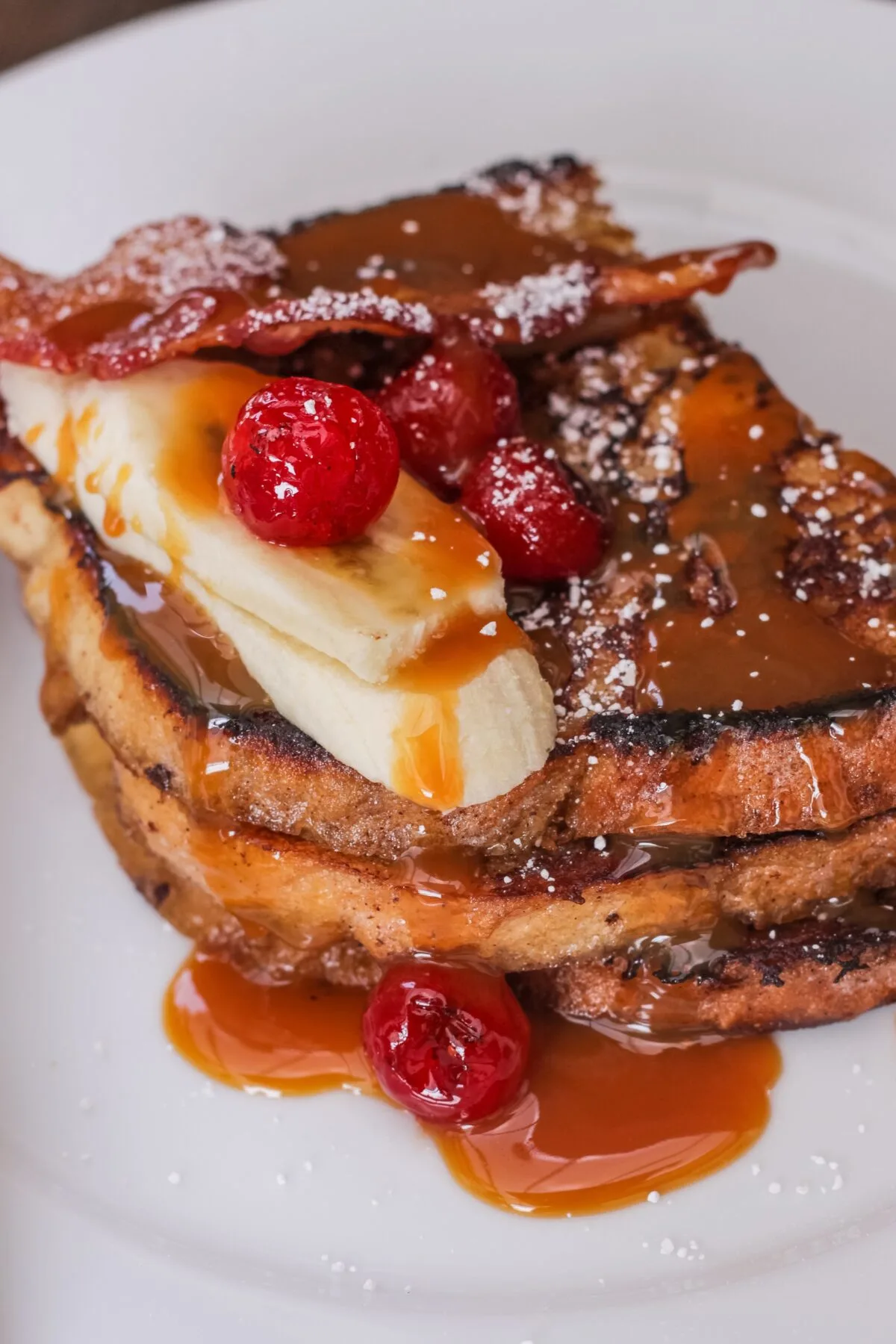 Bananas Foster French Toast is a decadent breakfast recipe served with blistered cherries and bacon for an easy twist on the classic.