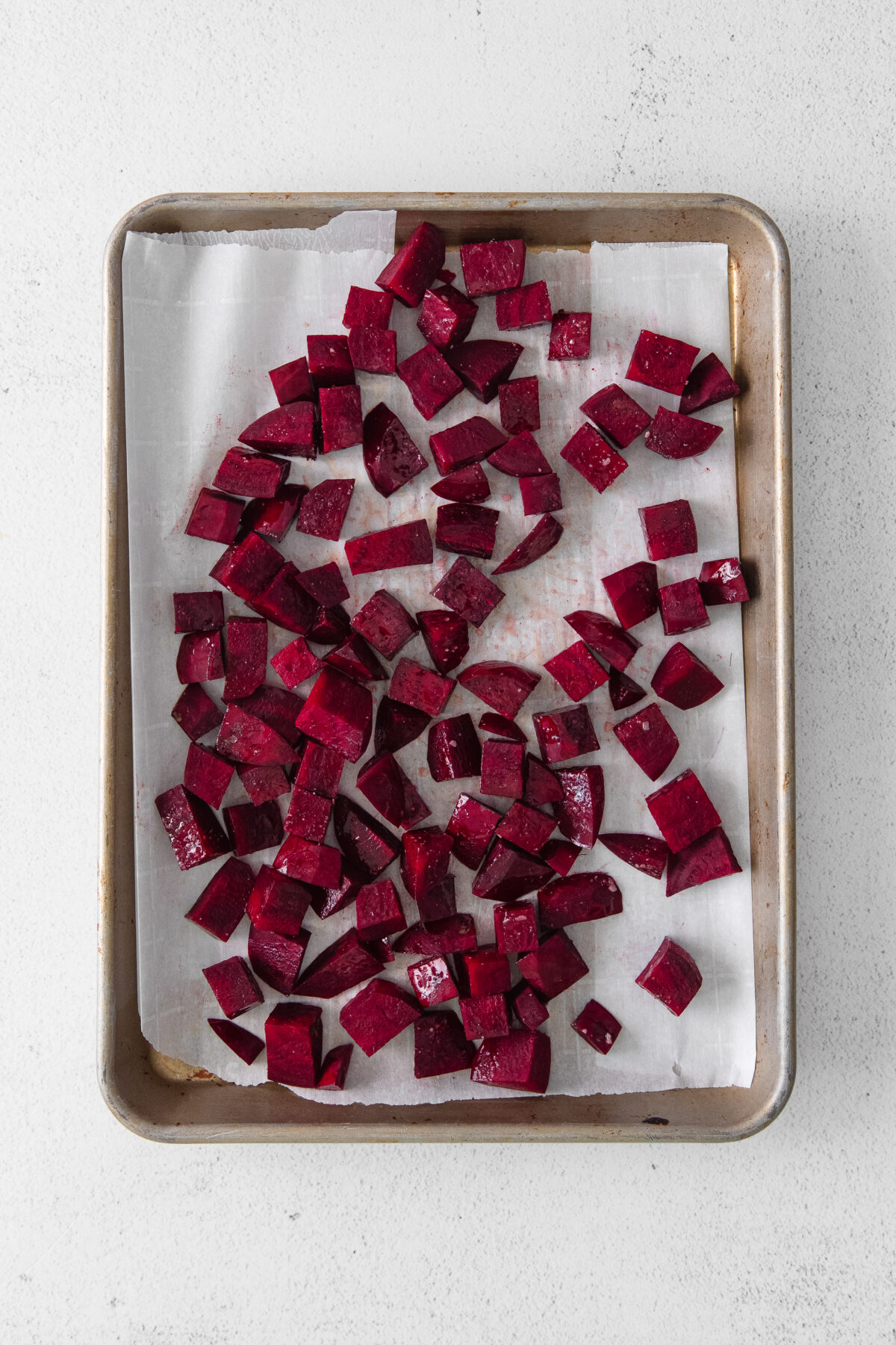 Chopped beets on a sheet pan lined with parchment paper.