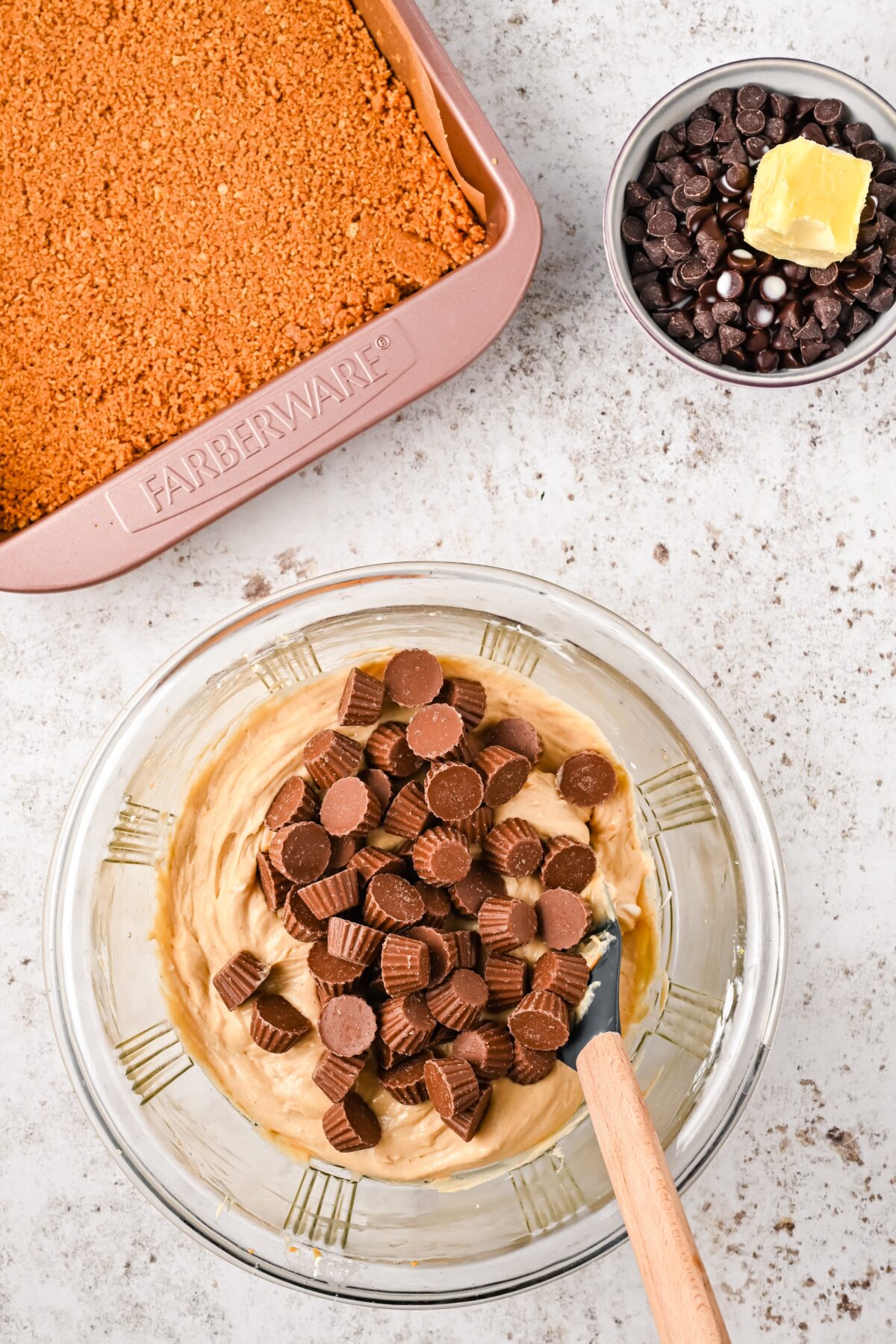 Mini peanut butter cups on top of the batter in a glass bowl.