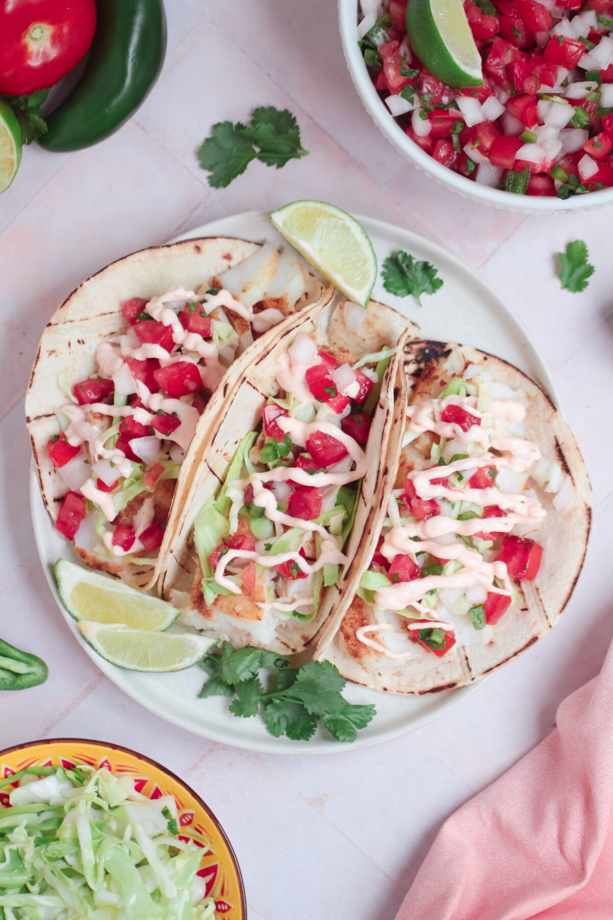 Make your next taco night extra special with these easy fish tacos topped with zesty cilantro lime slaw and sriracha sour cream!