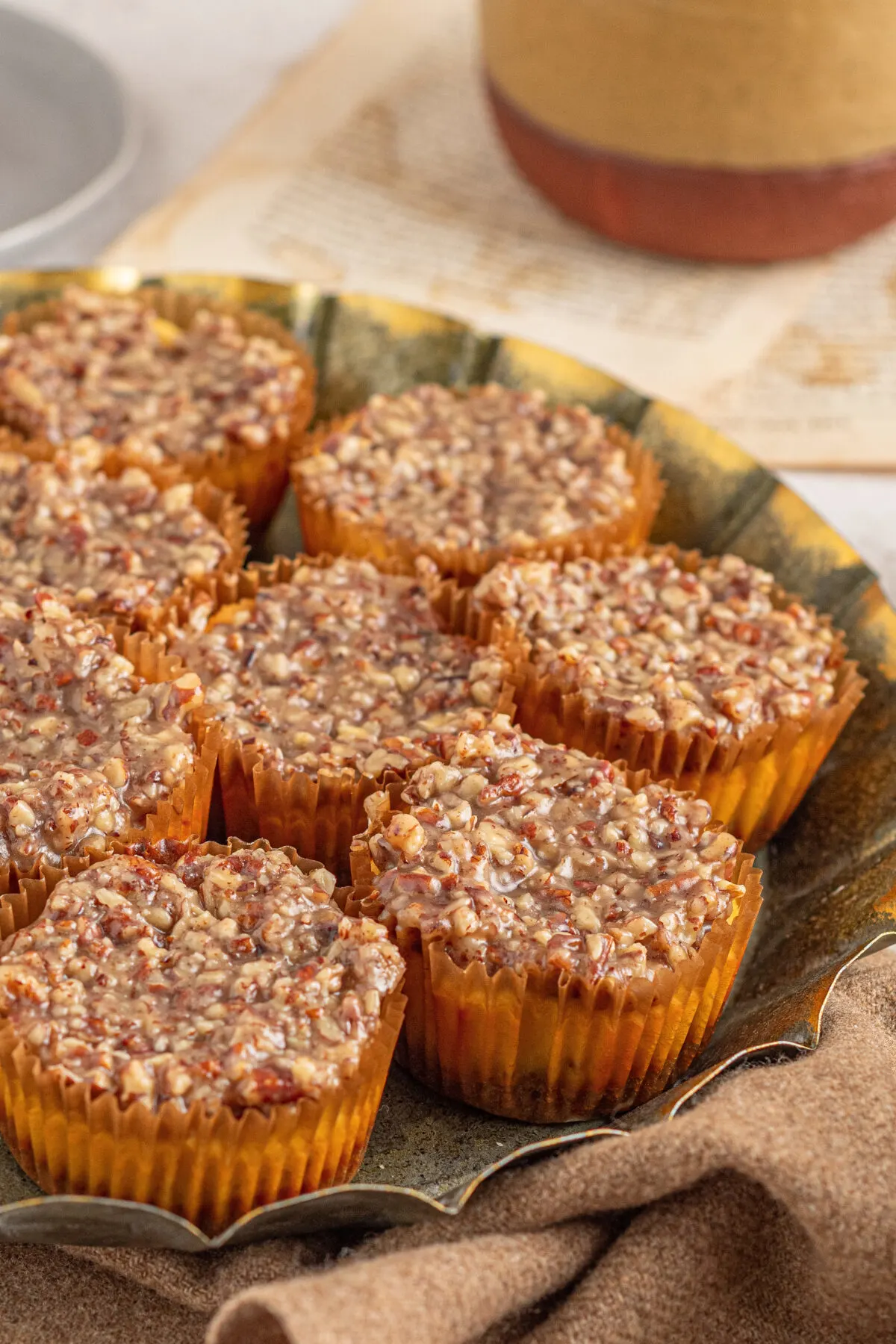 Indulge with mini pecan pie cheesecakes featuring a nutty graham cracker crust, smooth and creamy cheesecake, and a gooey pecan topping.