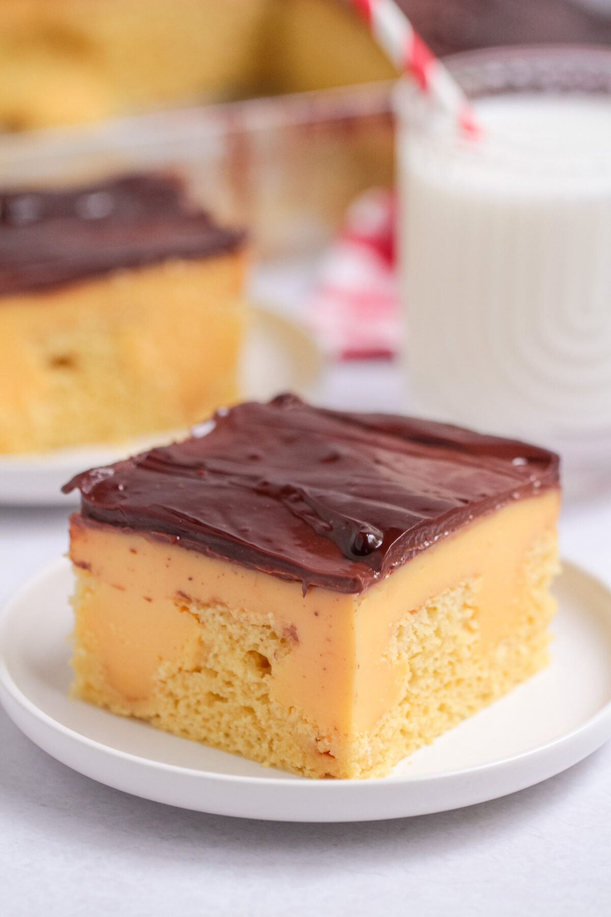This Boston Cream Poke Cake features yellow cake, classic vanilla custard, and chocolate ganache for a nostalgic bakery-inspired dessert.