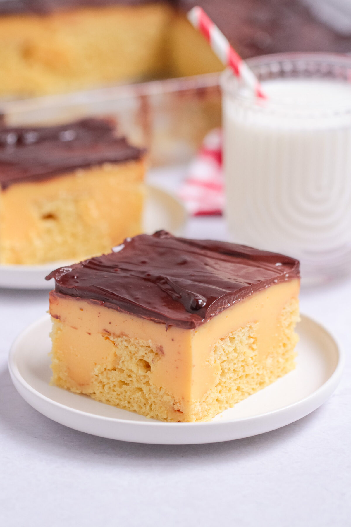 This Boston Cream Poke Cake features yellow cake, classic vanilla custard, and chocolate ganache for a nostalgic bakery-inspired dessert.