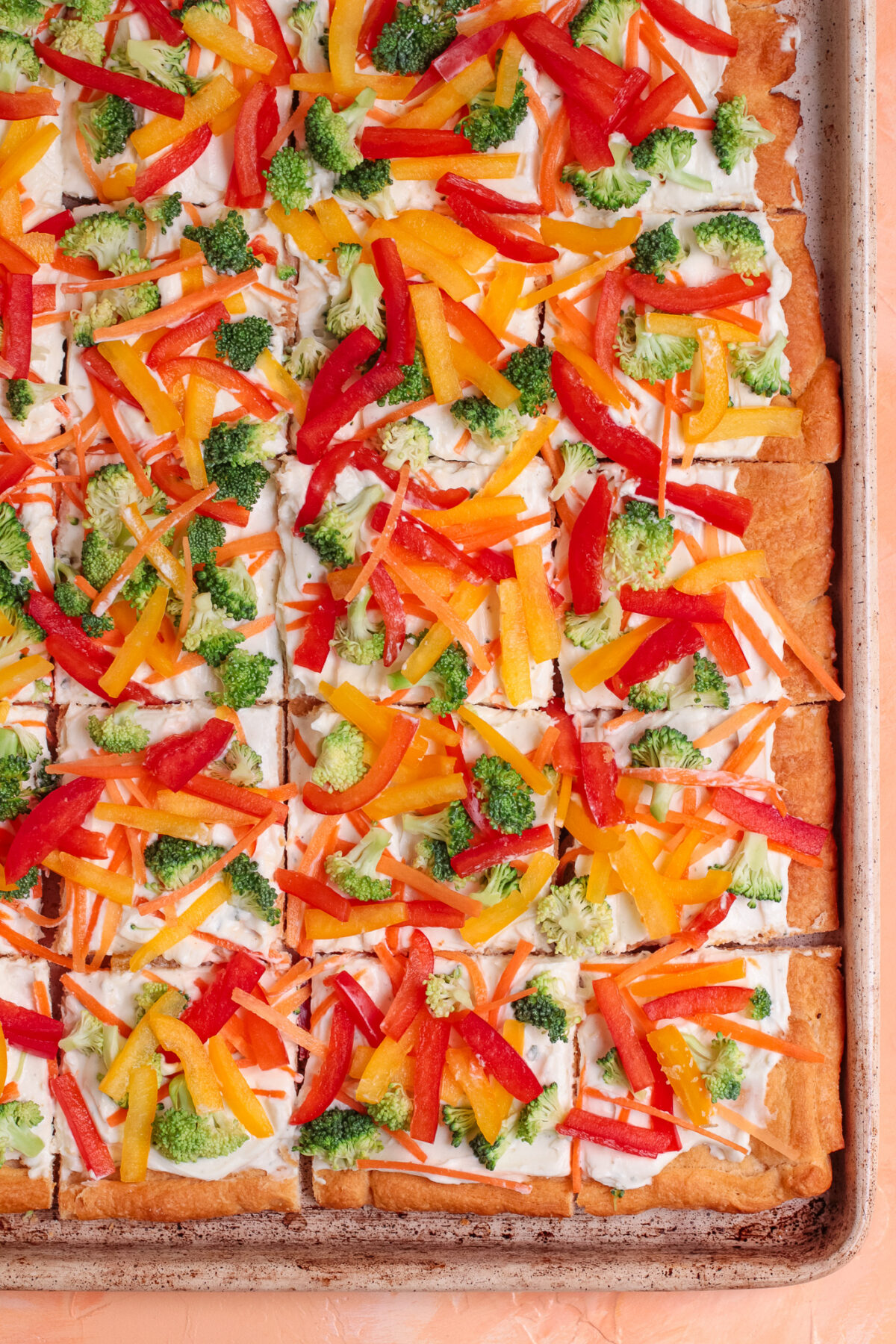 Easy cold veggie pizza with crescent roll crust, ranch cream cheese spread, broccoli, carrots, and bell peppers. Perfect for parties.